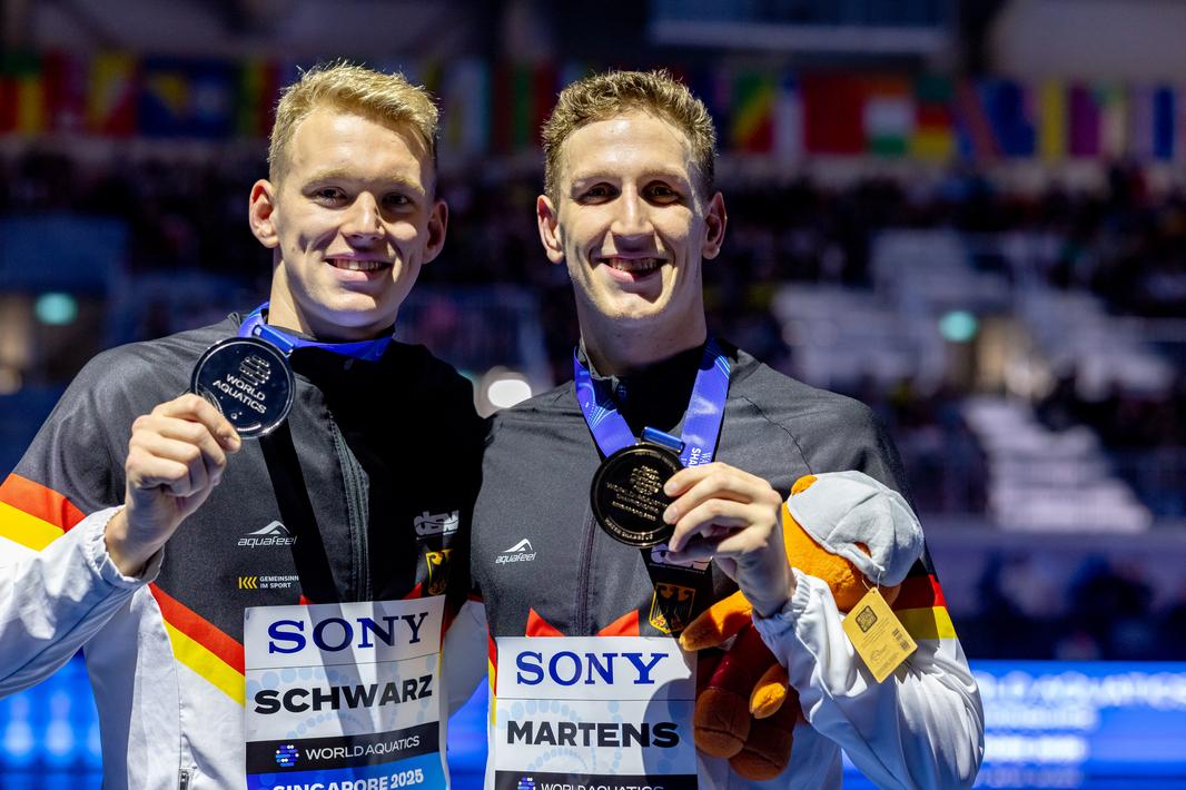 Lukas Märtens und Sven Schwarz posieren zusammen mit ihren WM-Medaillen
