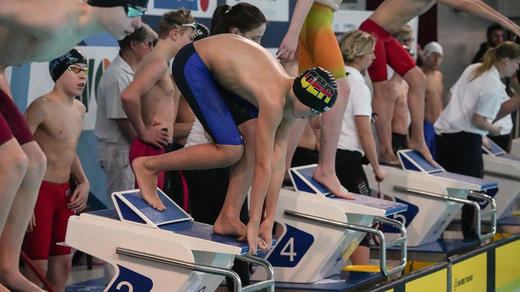 Ein Schwimmer wartet auf dem Startblock auf seinen Staffelstart.