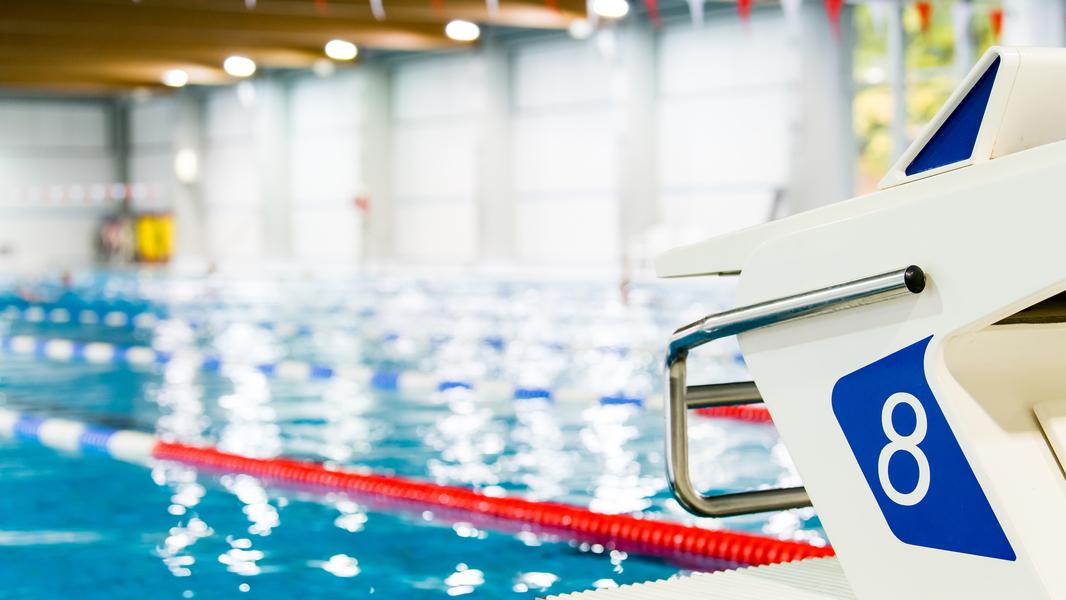 Startblock Nummer 8 an einem Schwimmbecken mit blauen Wasser und Schwimmbahnen im Hintergrund.